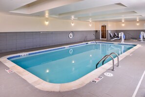 Une piscine intérieure avec des lignes de démarcation bien visibles, un poste de surveillance pour le sauveteur et une entrée vers les vestiaires.