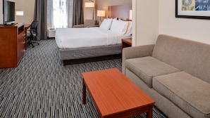 A hotel room with a bed, a sofa, a desk with a TV, a chair, and a lamp. - Holiday Inn Express & Suites York by IHG (York)