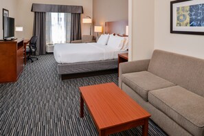 A hotel room with a bed, a sofa, a desk with a TV, a chair, and a lamp. - Holiday Inn Express & Suites York by IHG (York)