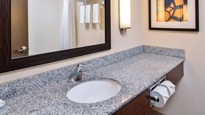 A bathroom with a granite countertop sink, a mirror, a towel rack, and a framed abstract painting. - Holiday Inn Express & Suites York by IHG (York)