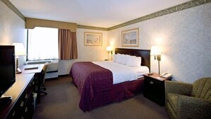 A hotel room with a bed, a desk, a chair, and two bedside lamps.