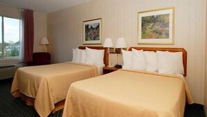 A hotel room with two beds, a window with a view, and two paintings on the wall.