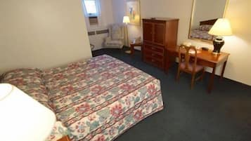 A bedroom with a bed, a desk, a chair, a dresser, and a mirror.