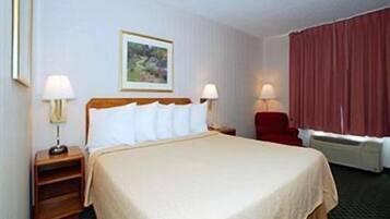 Comfortable room with a neatly made bed, bedside tables, and a chair, featuring a framed picture on the wall.