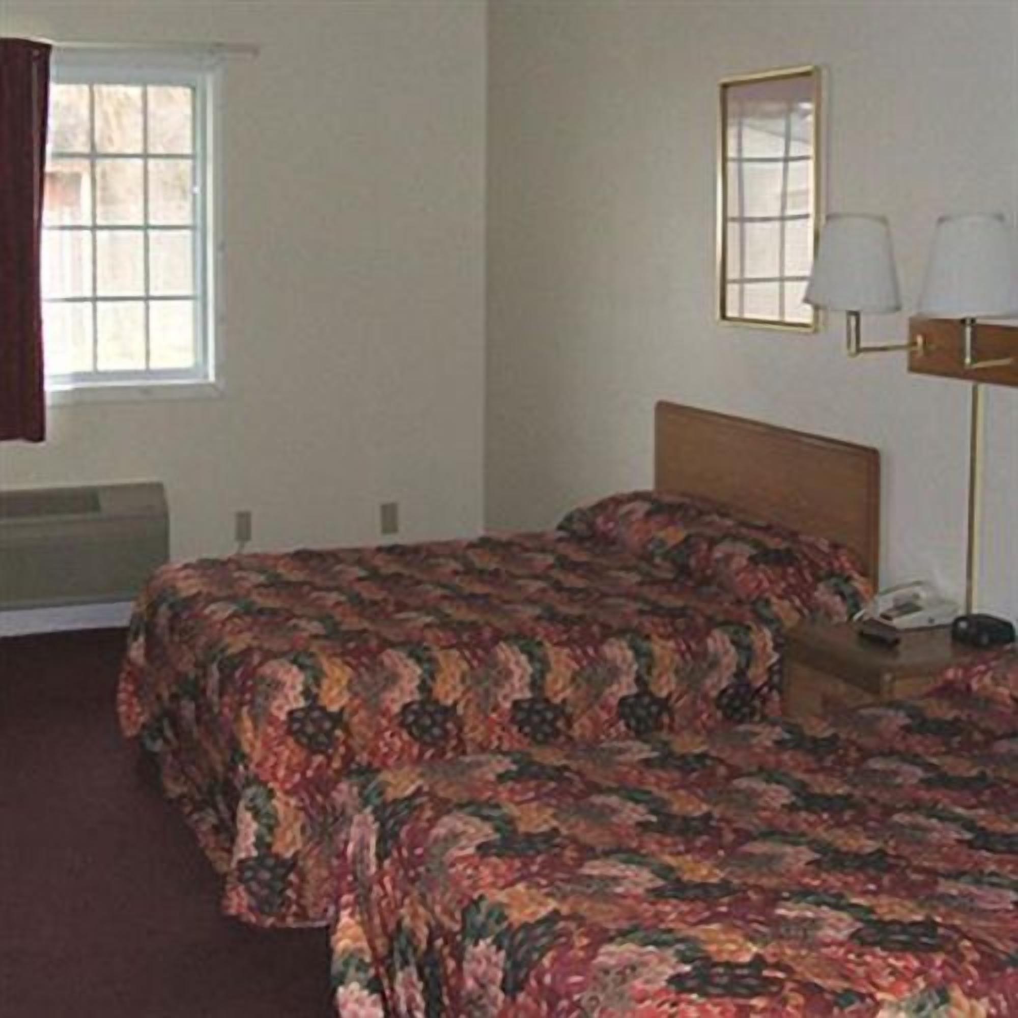 Une chambre d’hôtel avec deux lits, une table de chevet, une lampe et une fenêtre.