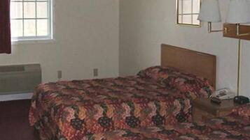 Une chambre d’hôtel avec deux lits, une table de chevet, une lampe et une fenêtre.
