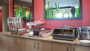 Una barra de desayuno con diversos alimentos, un tostador y un espejo que refleja la habitación.