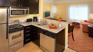 Una habitación de hotel compacta con kitchenette, comedor y sala de estar.