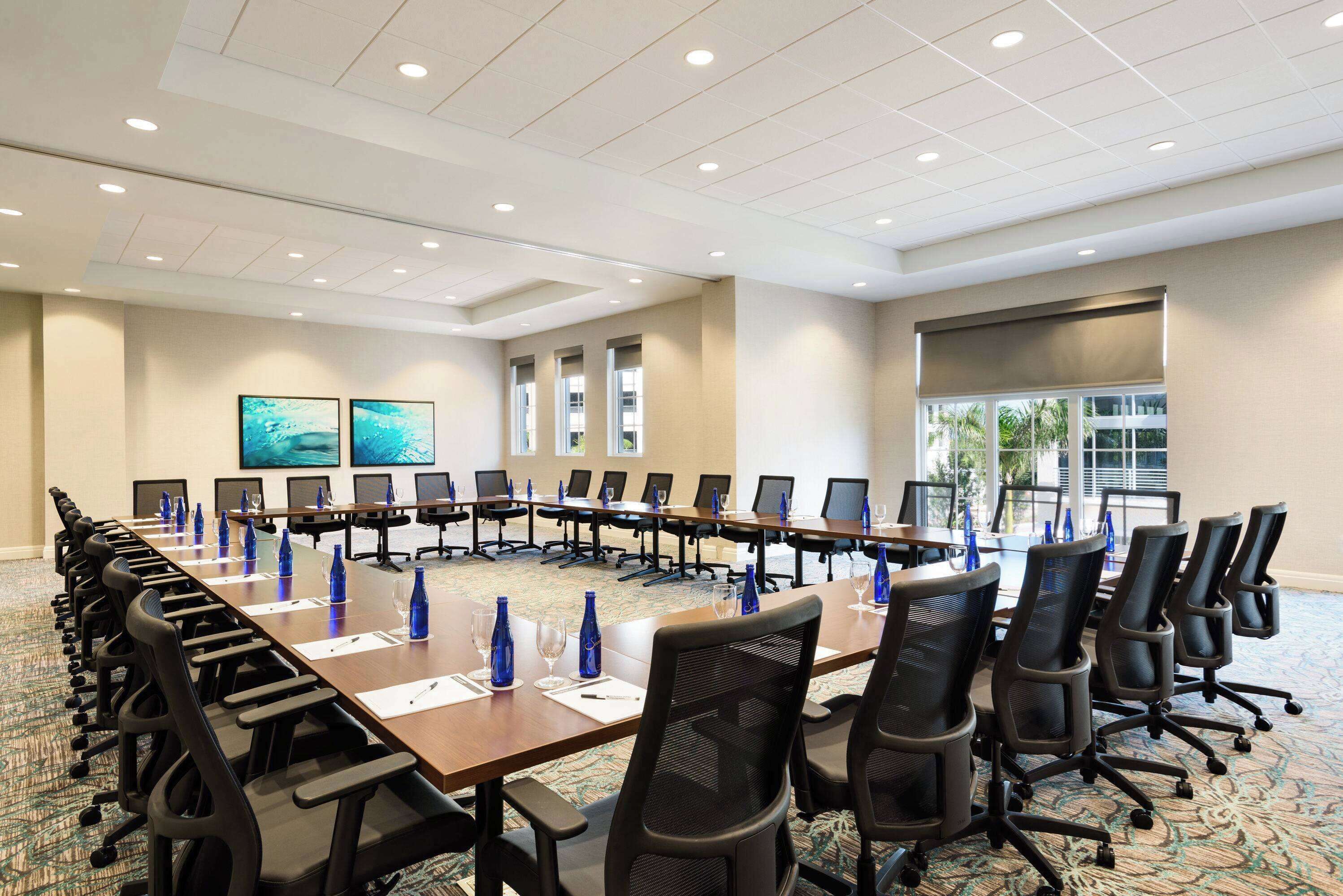 A conference room with a long table, multiple chairs, and blue water bottles.