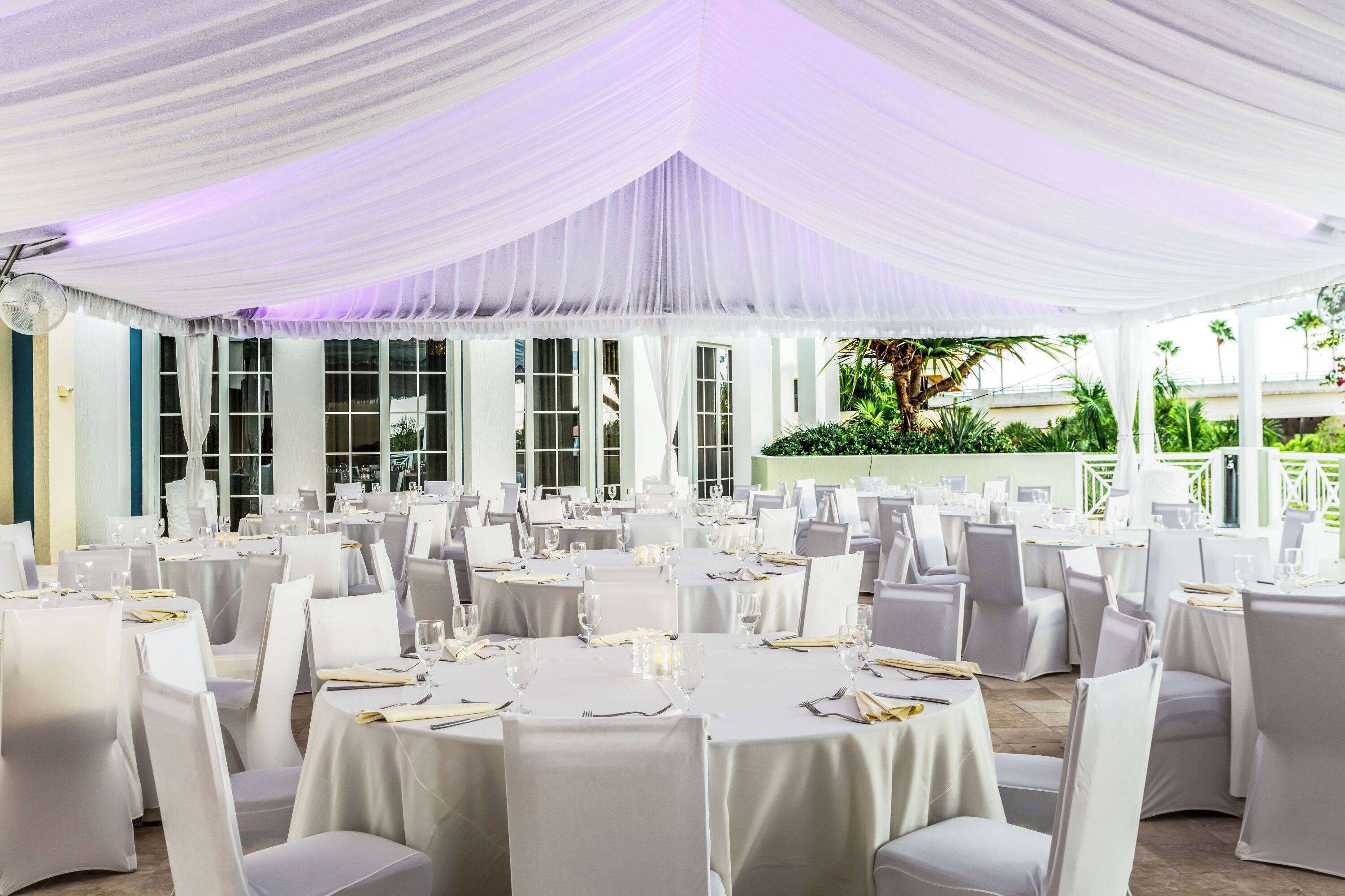 Un salón de banquetes con mesas redondas, manteles blancos y sillas.