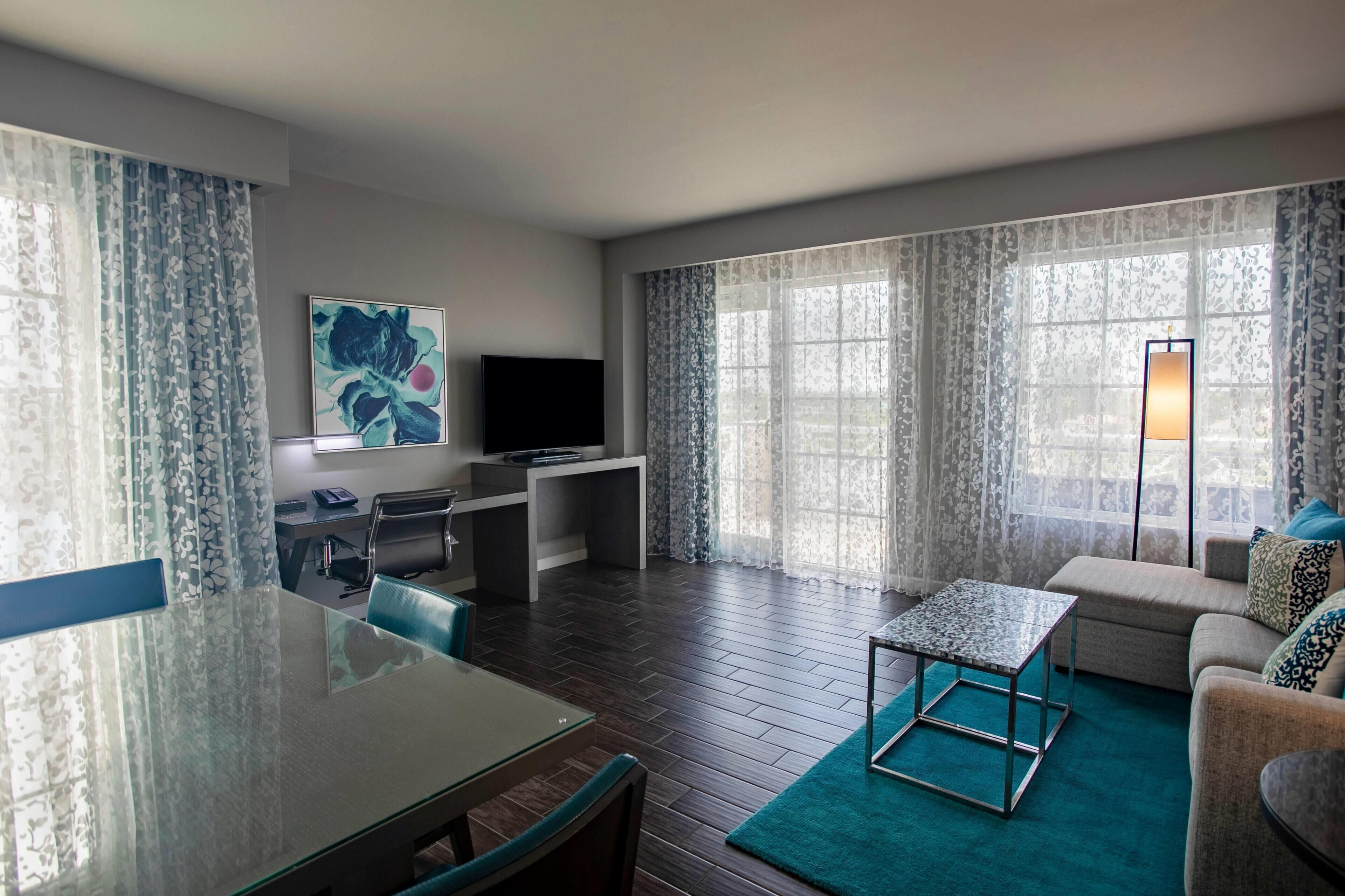 A modern living room with a flat-screen TV, a dining table, and a sofa.