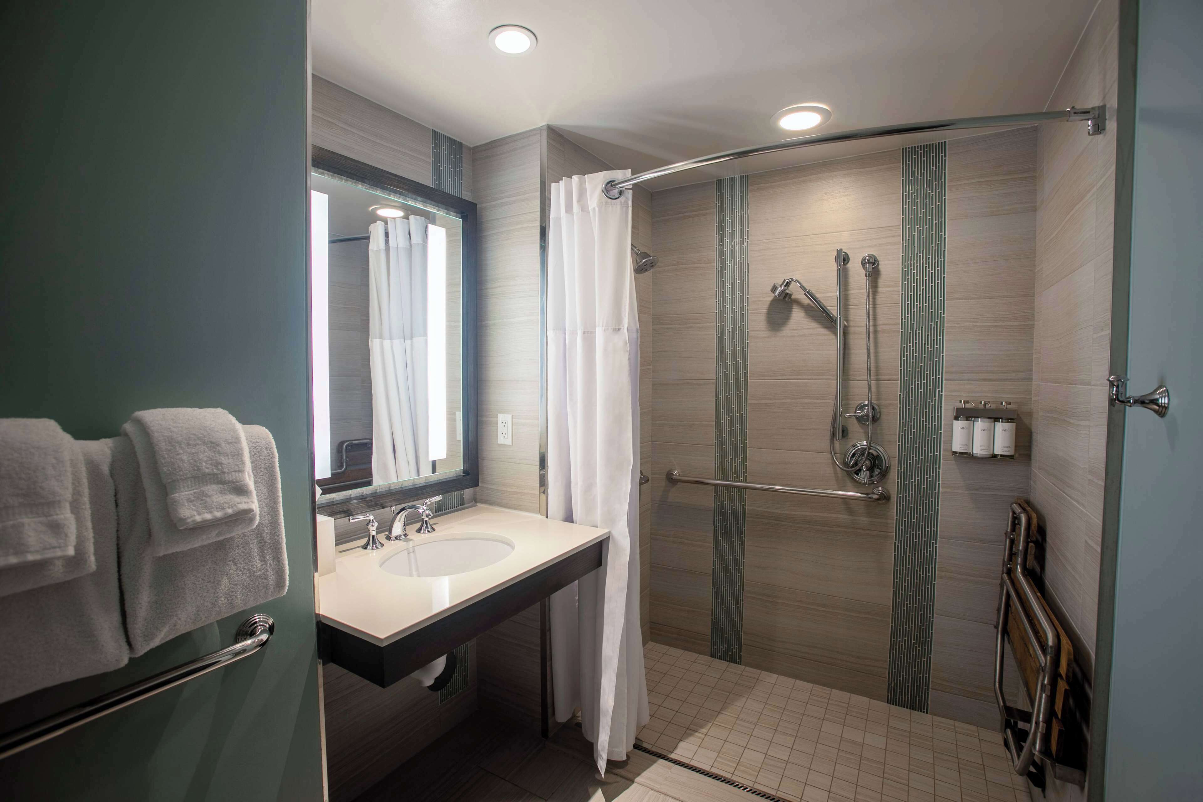 Un baño moderno con ducha, lavamanos y espejo.