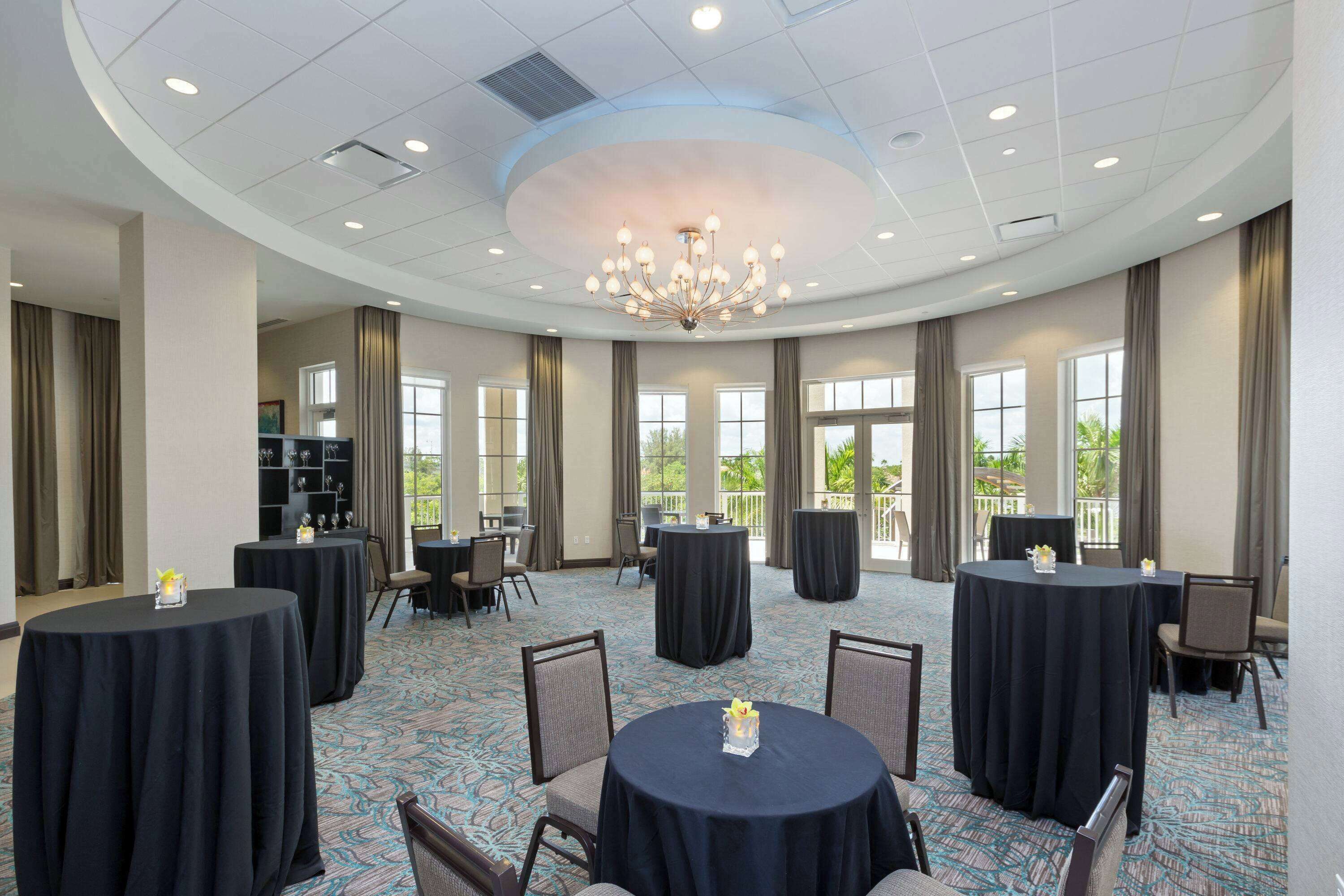 A conference room with round tables, chairs, and a chandelier.