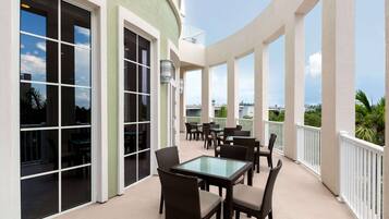 A covered outdoor patio with tables and chairs, large windows, and a view of the surrounding area.