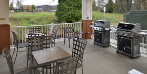 Une terrasse extérieure équipée d’un barbecue, de sièges et offrant une vue sur les environs.