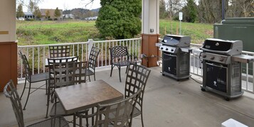 An outdoor patio with a grill, seating, and a view of the surrounding area.
