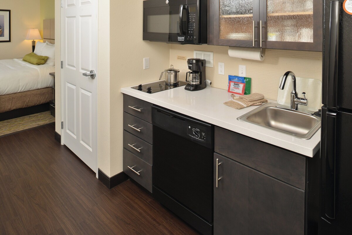 Una kitchenette compacta con microondas, cafetera y lavabo.