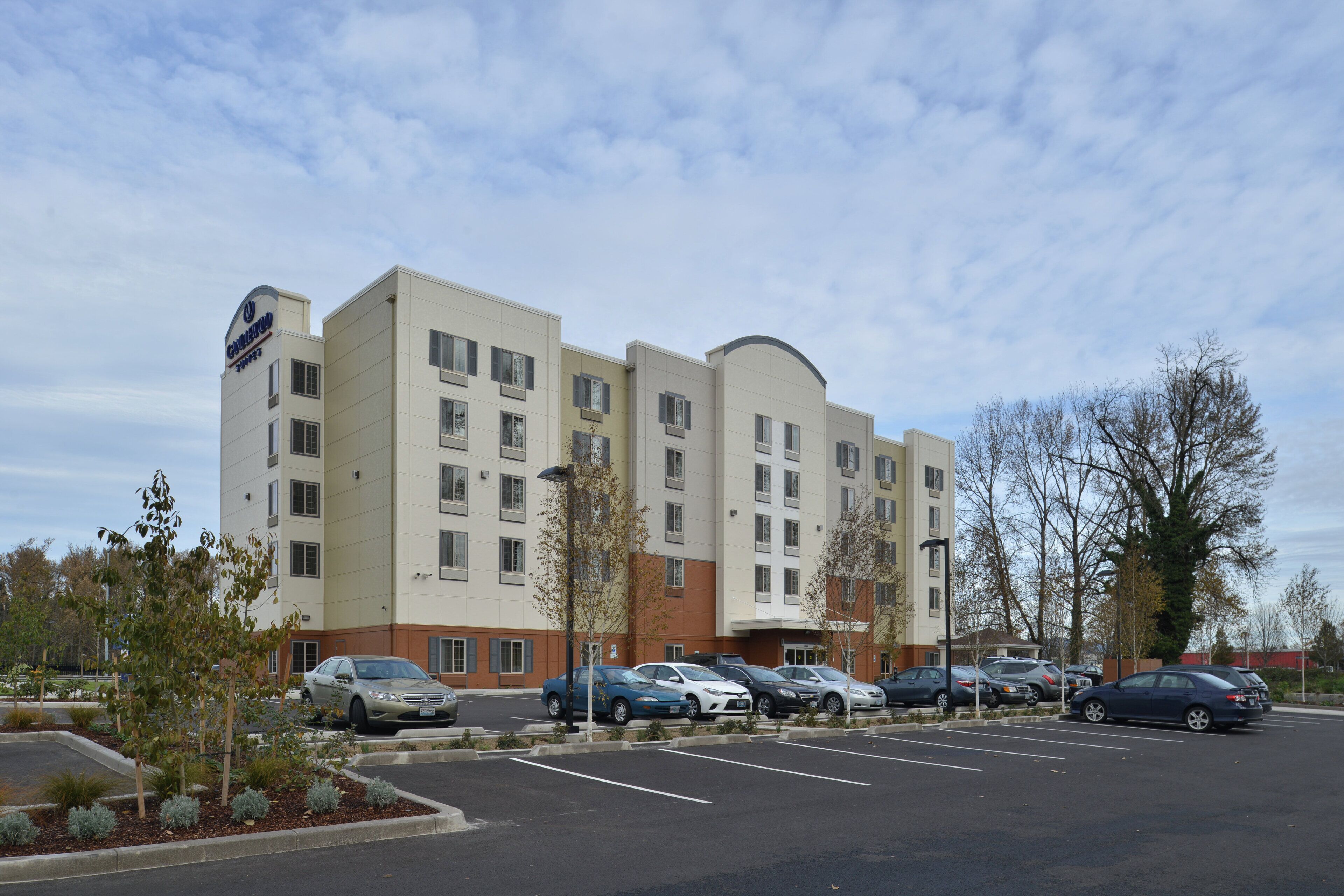 A multi-story hotel with a parking lot in front.
