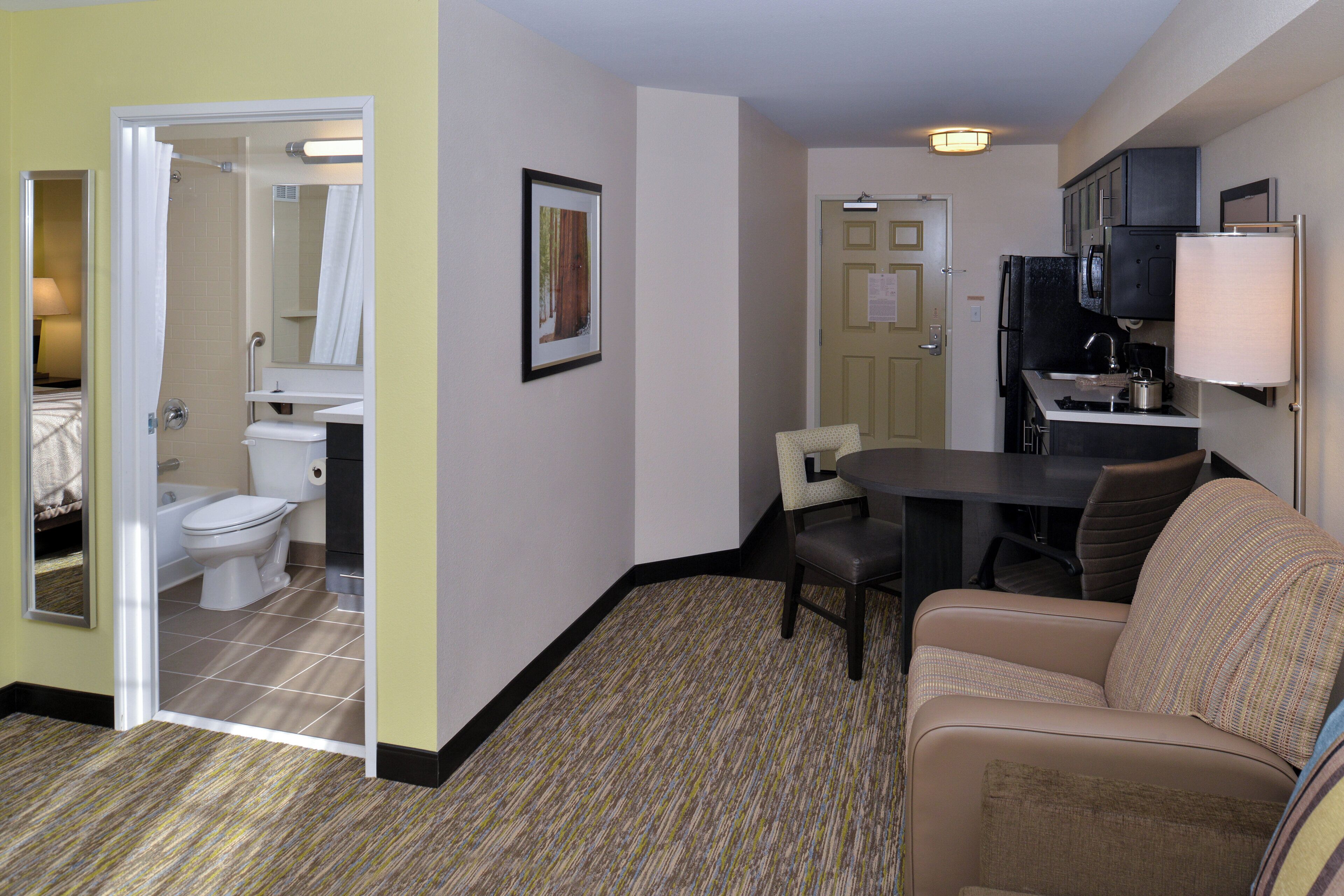 Une chambre d’hôtel de taille réduite, dotée d’une salle de bain, d’un coin repas et d’une kitchenette.