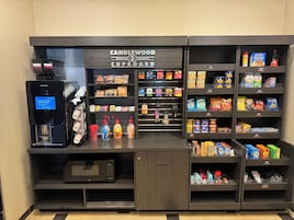 A self-service kiosk with a coffee machine, a microwave, and a variety of snacks and beverages.