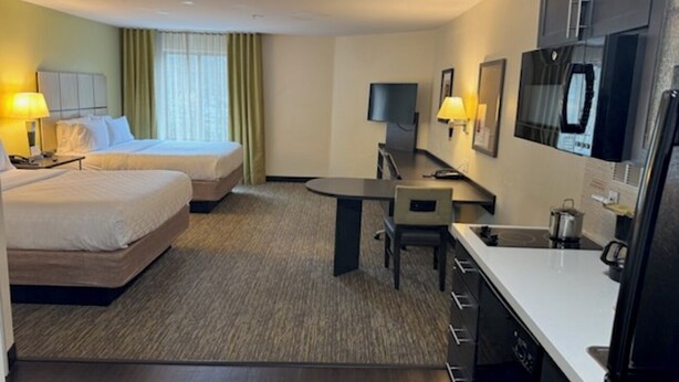 A hotel room with two beds, a desk, a chair, a TV, and a kitchenette. - Candlewood Suites Eugene Springfield by IHG (Eugene)