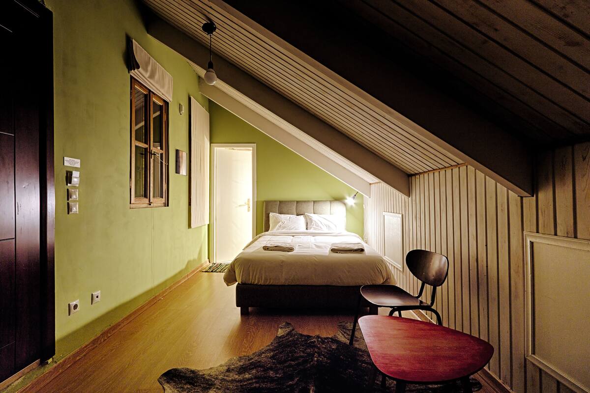 Une chambre à coucher avec un lit, une chaise et un plancher en bois.