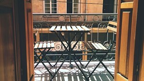 Ein Balkon mit Metallgeländer und zwei Holztischen.