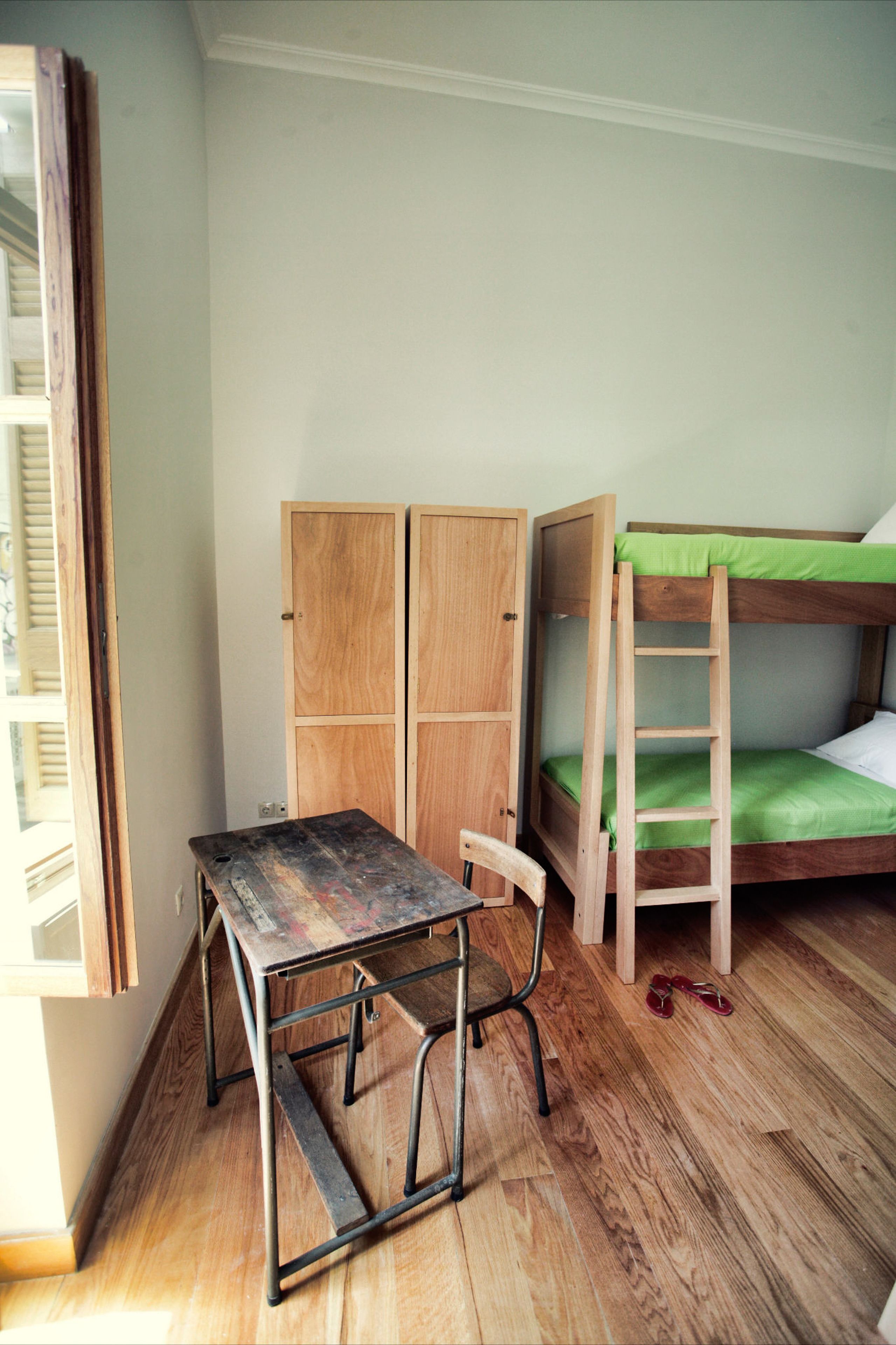 A room with a bunk bed, a desk with a chair, and a wardrobe.