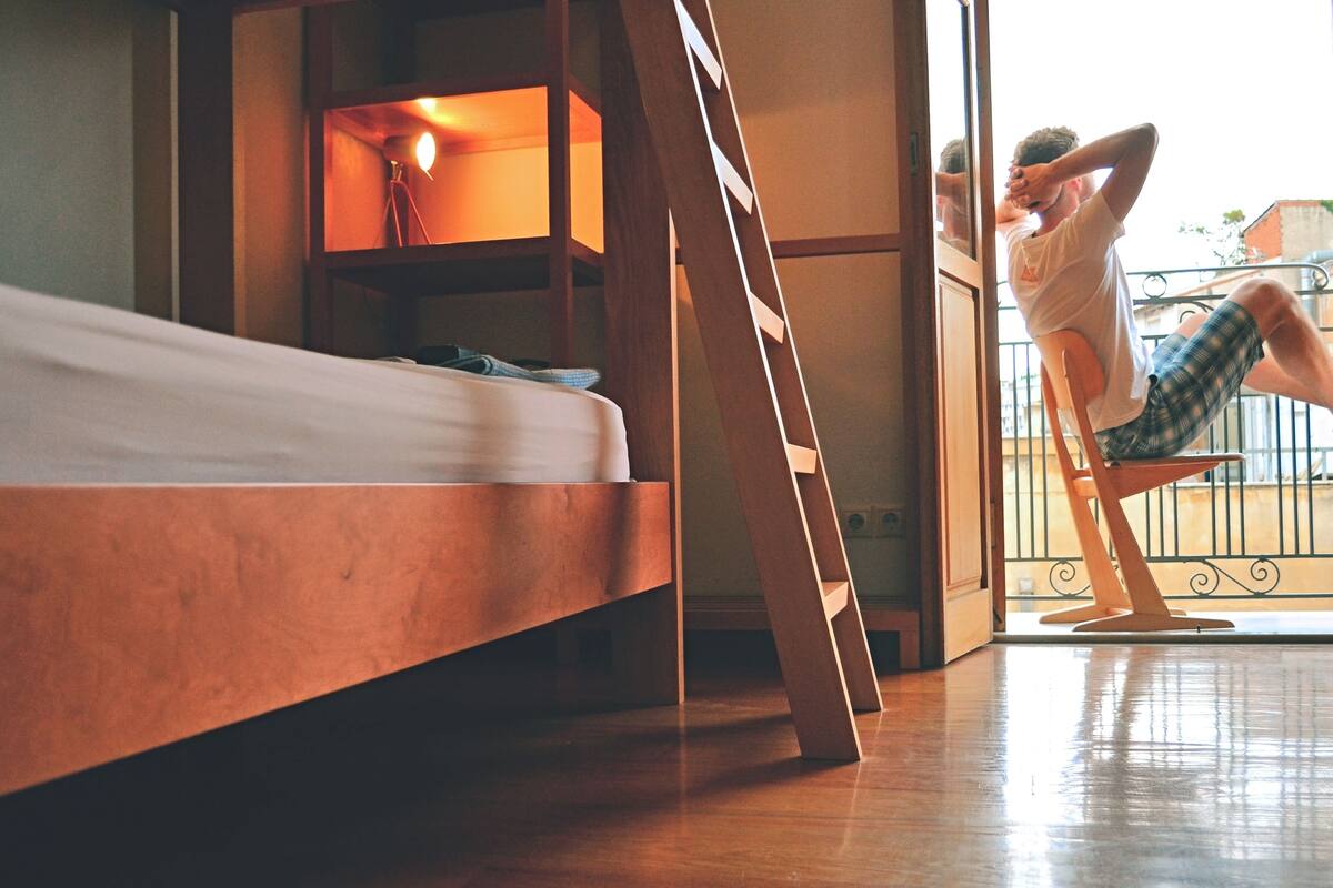 Une pièce avec un lit, une échelle en bois et un balcon doté d’une balustrade.