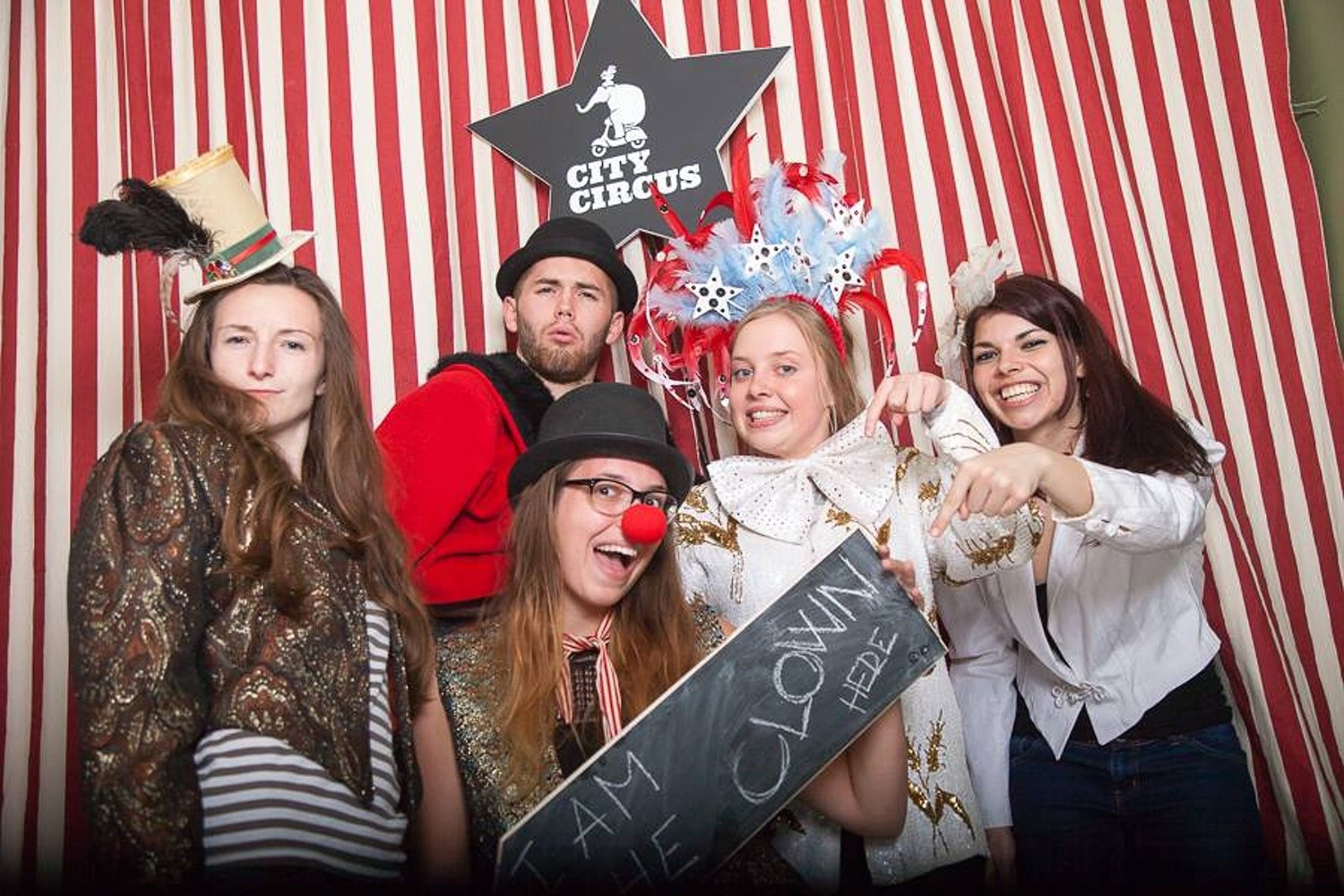 A group of people in front of a striped backdrop with a star and the text "CITY CIRCUS".