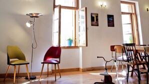Ein Zimmer mit Holzboden, Stuckdecke, Projektor und mehreren Stühlen.