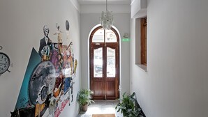 Ein Flur mit einer Holztür, einem Chandelier und einer Wand mit verschiedenen Postern und einer Uhr.