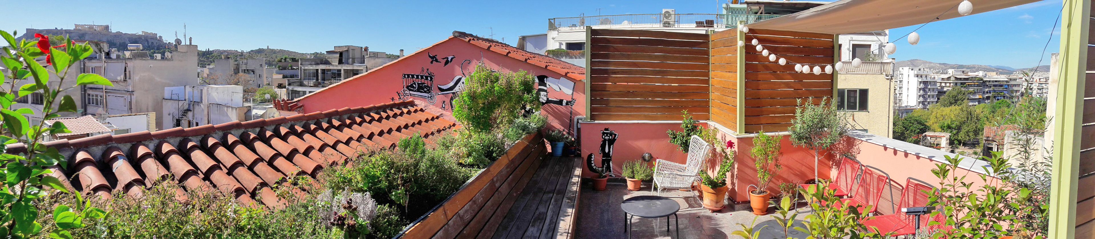 Eine Dachterrasse mit Terrakottafliesen, Pflanzgefäßen und Gartenmöbeln.