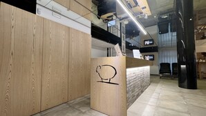 A reception desk with a wooden finish and a simple design, including a black line drawing of a bear. - Hotel Miramonti (Schio)