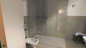 Un baño moderno con ducha envuelta en vidrio, lavamanos pedestal y bañera.