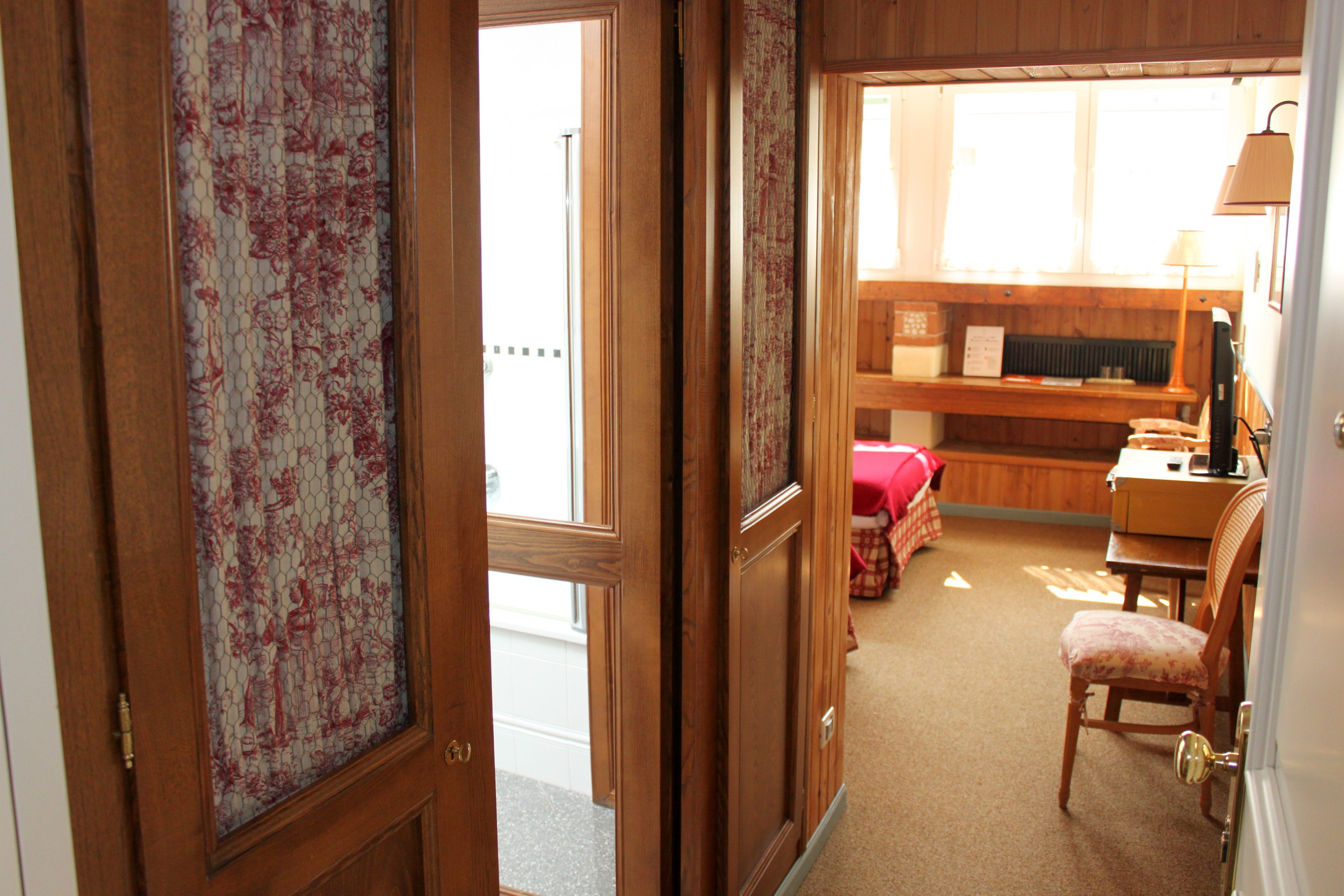 Una habitación con escritorio de madera, una silla, un radiador y una ventana.