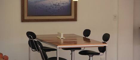 Un salón de conferencias con una mesa de madera, cuatro sillas y un cuadro en la pared.