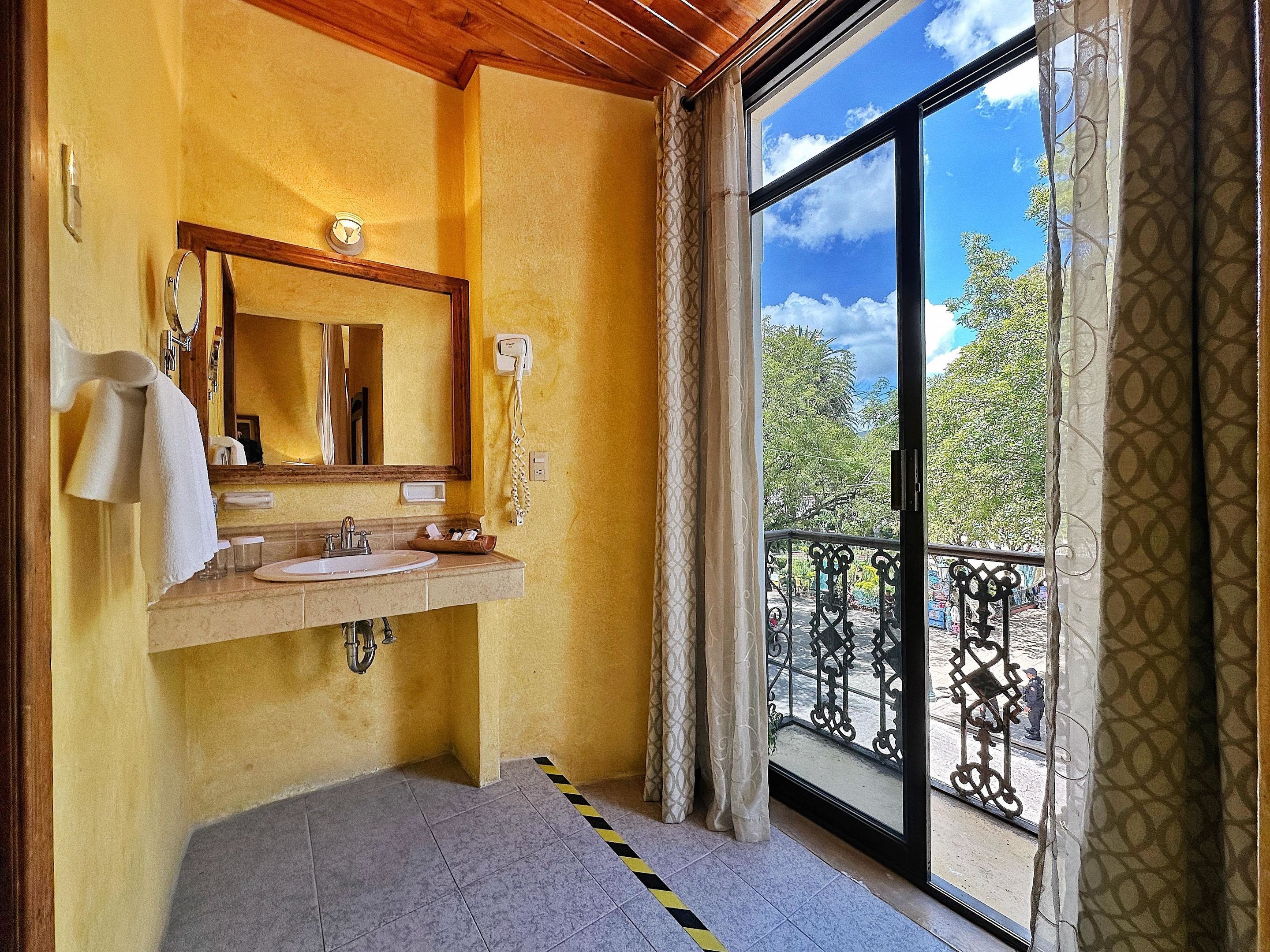 Un baño con lavamanos, espejo y vistas a un balcón con barandilla.