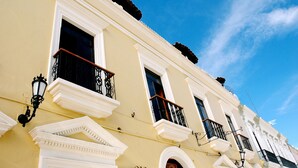Un edificio con adornos blancos, múltiples ventanas y balcones con barandillas negras.