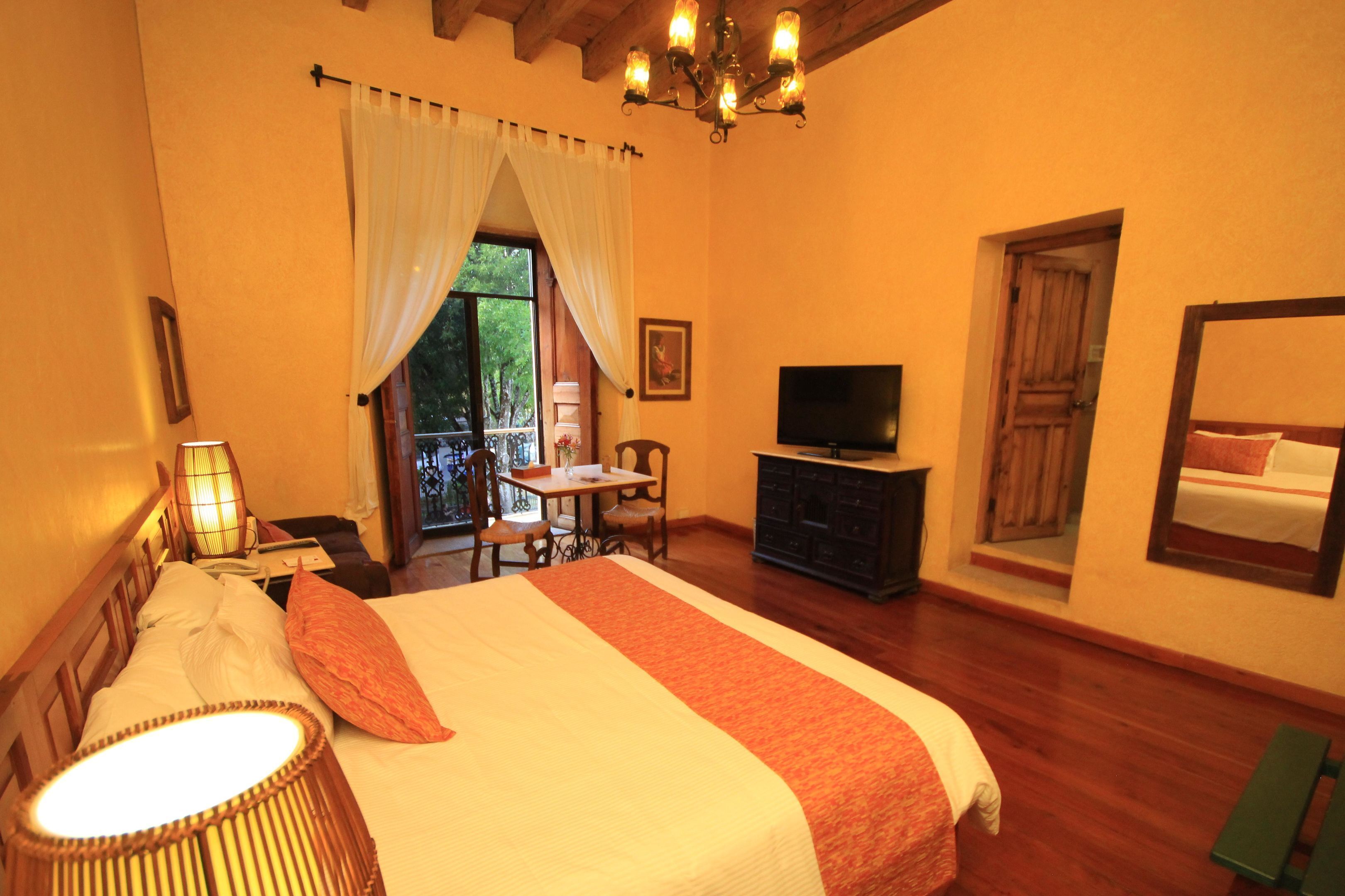A hotel room with a bed, a television, a desk, and a window with curtains.