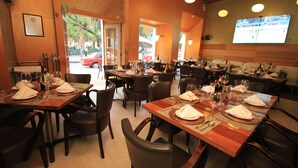 Un restaurante con varias mesas dispuestas para comensales, equipadas con copas de vino y cubiertos.
