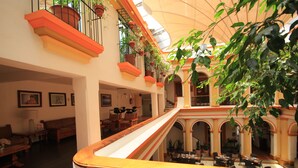 Un atrio amplio con una escalera central, varias zonas de estar y una diversidad de plantas en macetas.