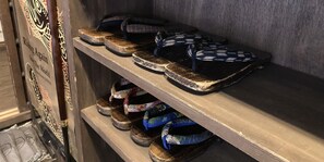 A wooden shelf with various pairs of slippers and sandals. - Kyoto Miyabi Inn -Only one group a day- (Kyoto)