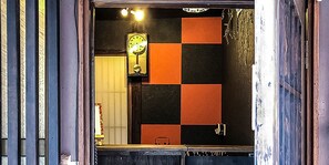 A bathroom with a checkered black and orange wall, a clock, and a mirror. - Kyoto Miyabi Inn -Only one group a day- (Kyoto)