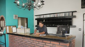 Un mostrador de recepción con encimera de ladrillo, un monitor de computadora y un estante para CDs.