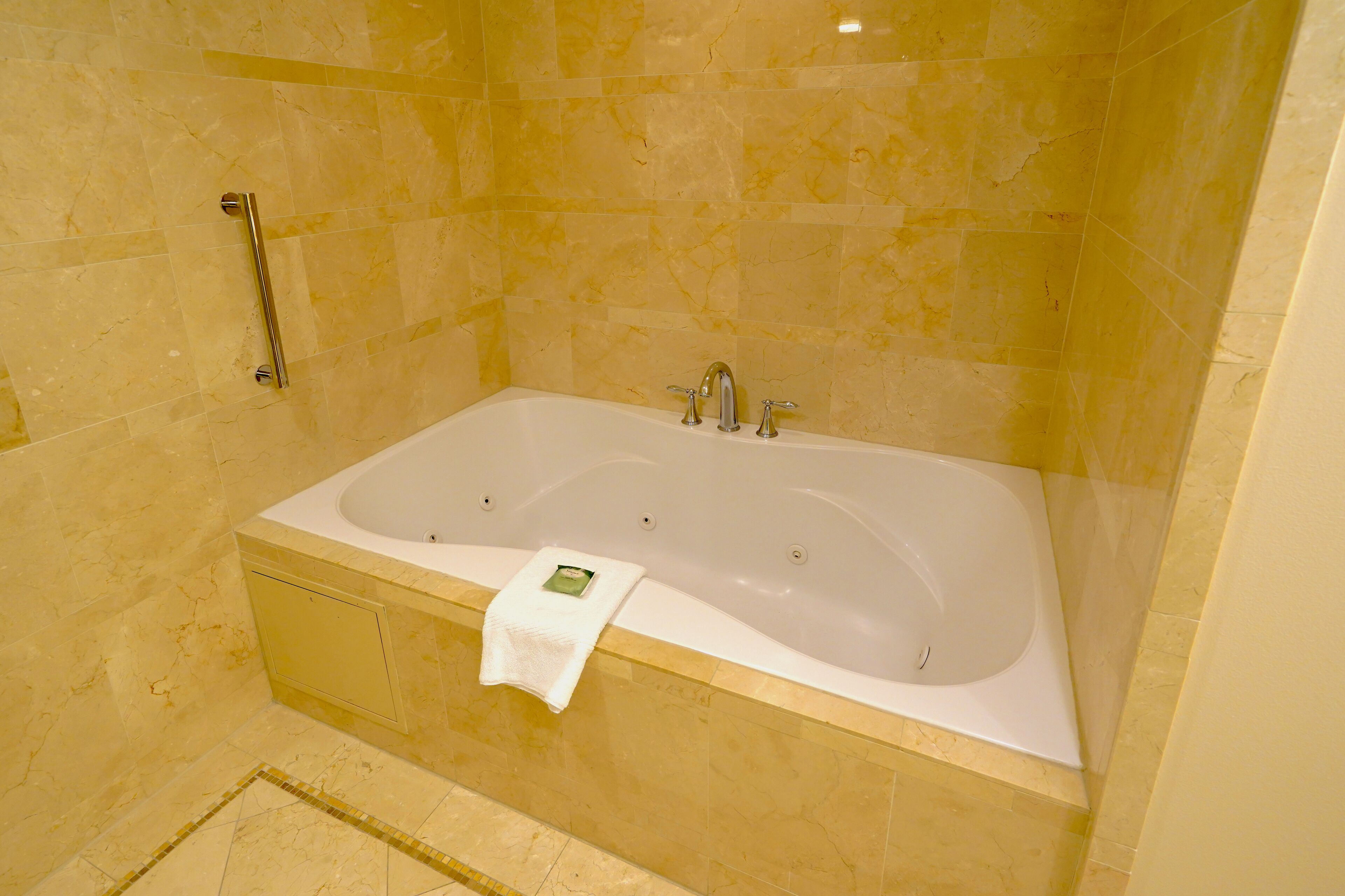 Une salle de bain moderne avec une grande baignoire, une barre d’appui et un porte-serviettes.