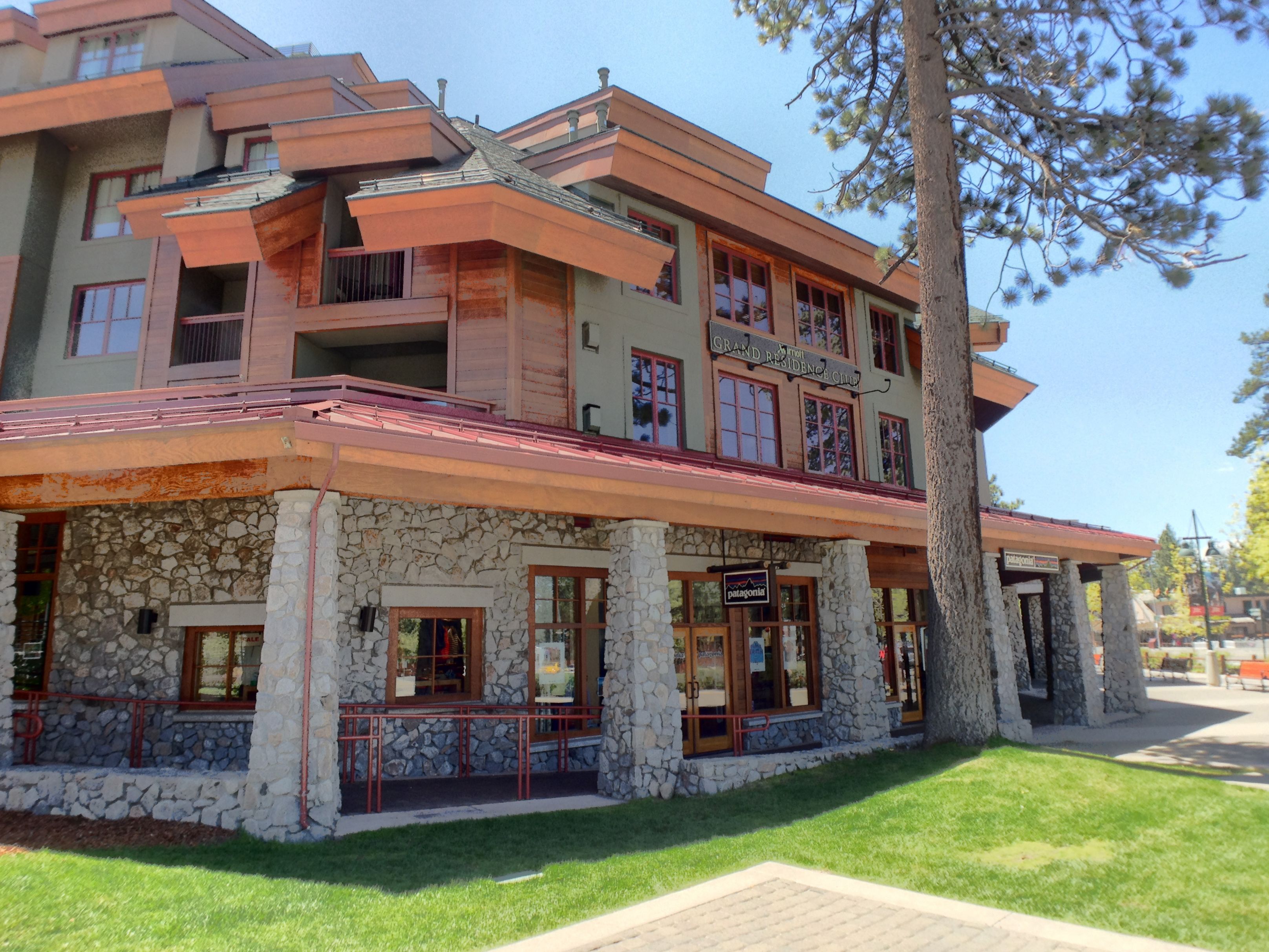 A multi-story building with a stone facade, multiple balconies, and a red roof.