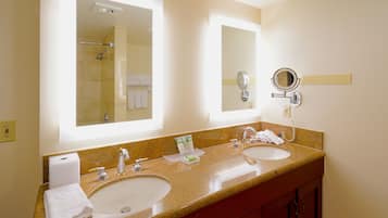 A hotel bathroom with two sinks, a large mirror, and a towel rack.