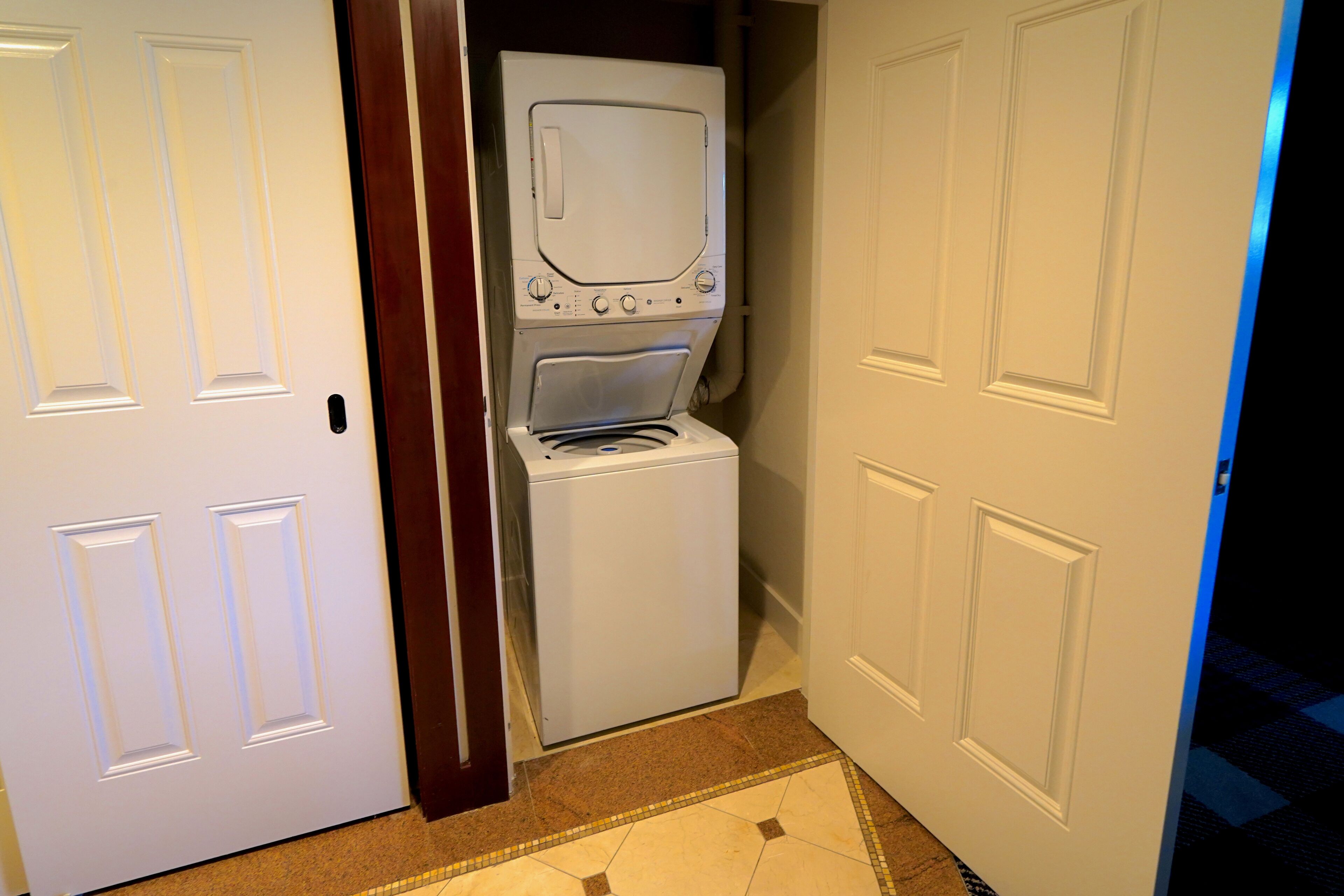 Une buanderie équipée d’un lave-linge et d’un sèche-linge, avec une porte et un sol carrelé.