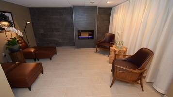 A modern living room with a fireplace, leather sofas, and a wooden chair.